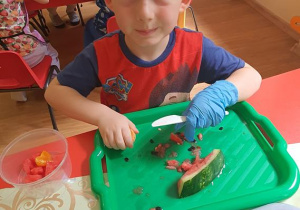 Filip kroi owoce do swojej sałatki owocowej.